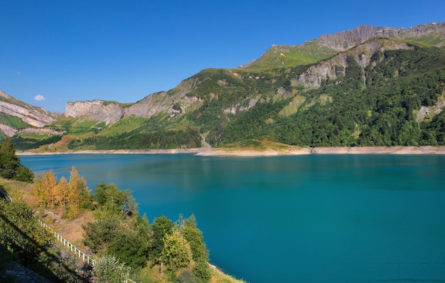 Lago de Roselend e água turquesa azul cercada por montanhas nos Alpes franceses sob