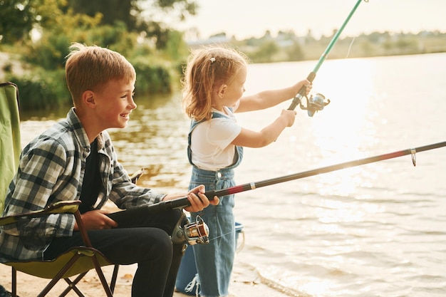 Lago de tamanho médio Menino com sua irmã pescando ao ar livre no verão juntos