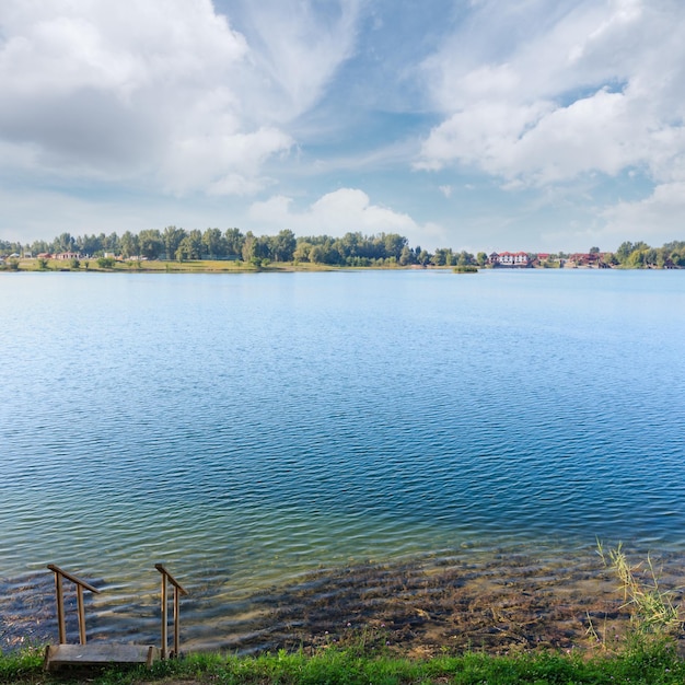 Foto lago de verão praia calma com escarpamentos de madeira para a água