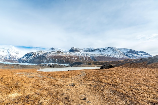 Lago e prado congelados dos vales das montanhas perto da geleira na Islândia