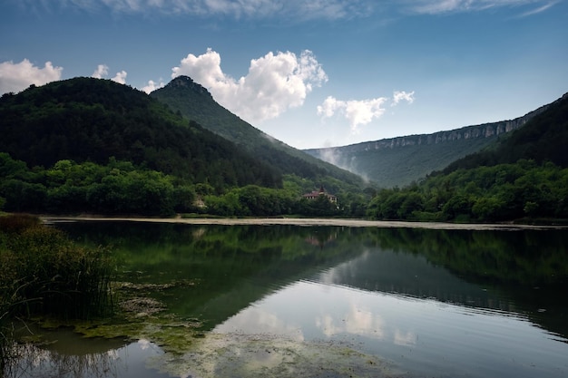 Lago escuro e nevoento com colinas após a chuva