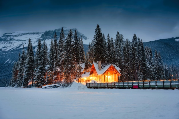 Lago Esmeralda con cabaña de madera brillando en un bosque de pinos nevados en invierno en el parque nacional Yoho