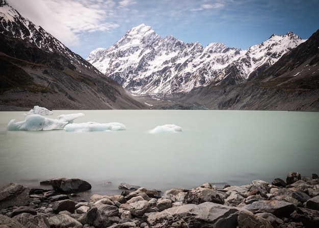 Lago glacial con trozos de hielo flotando en la escena del agua con el pico de la montaña en segundo plano.