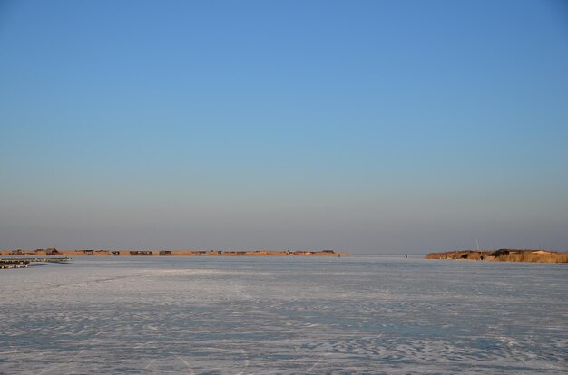 Lago helado y cabañas con juncos