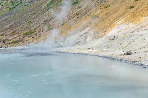 Lago mineralizado caliente con aguas termales y fumarolas humeantes en la caldera del volcán Golovnin en la isla de Kunashir