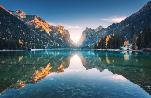 Lago de montaña al atardecer en otoño Paisaje con lago cielo azul con reflejo dorado de la luz del sol en el agua árboles con hojas coloridas rocas altas en otoño Viajes en Dolomitas Italia Naturaleza