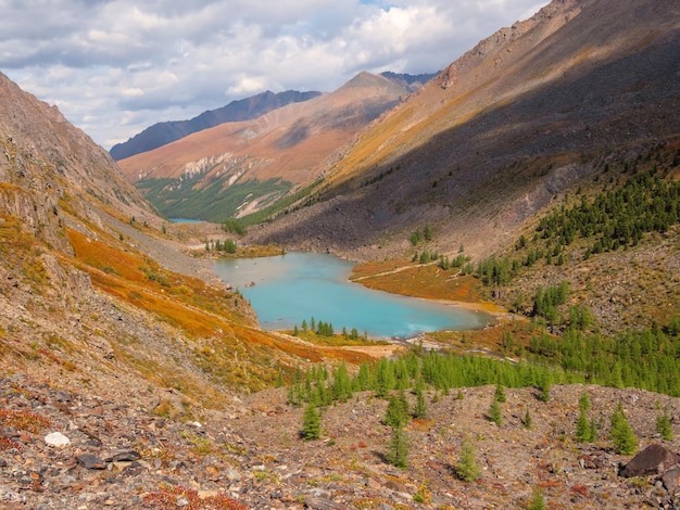 Lago de montaña azul en la caldera Cordillera contra un cielo nublado La caldera de un volcán extinto está rodeada por una cadena montañosa Meseta de altura amarilla soleada de otoño