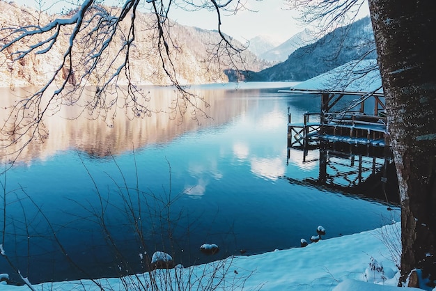 Lago de montaña en la casa del muelle de invierno bajo la nieve