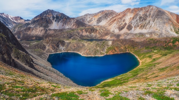 Lago de montaña Glen en forma de corazón. Paisaje verde atmosférico con lago en el valle de flores de alta montaña. Gran paisaje con lago de montaña en Highland Glen.