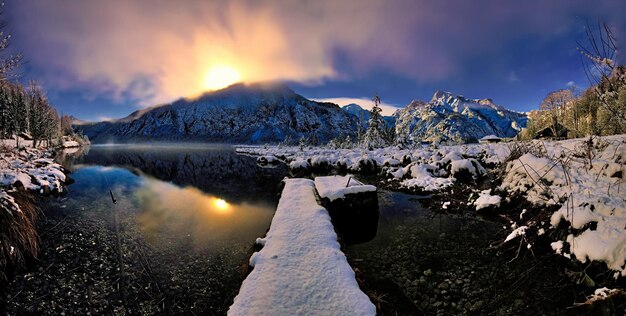 un lago de montaña nevado con un puente en el fondo