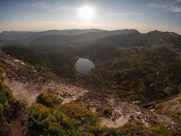 El lago de montaña ovalado muy abajo en el valle al atardecer