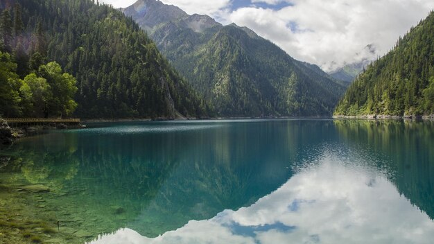 un lago de montaña con un reflejo en él y las montañas en el fondo