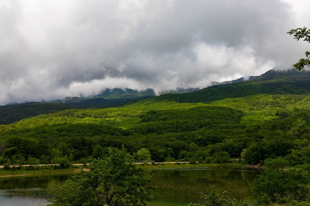 Lago de montaña con vistas a la montaña y nubes.