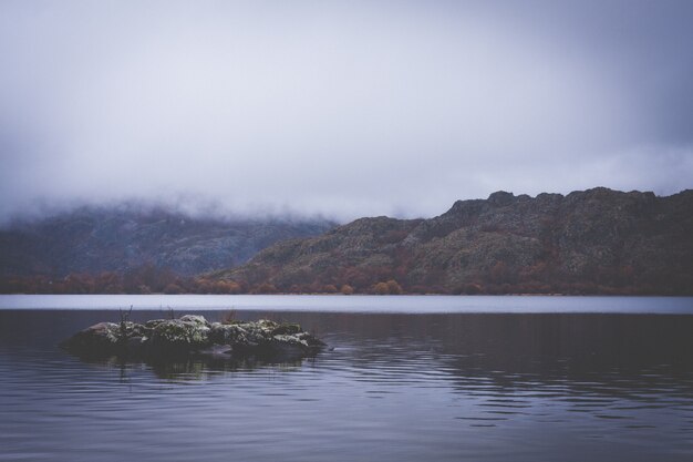 Lago entre montañas con nubes bajas.