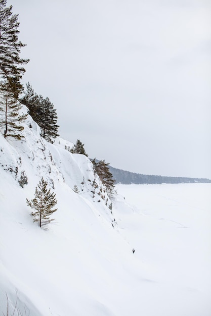 Un lago o río congelado en invierno. Cerca del bosque y las montañas en la nieve. Hermosos paisajes invernales. Viajes de invierno en la naturaleza.