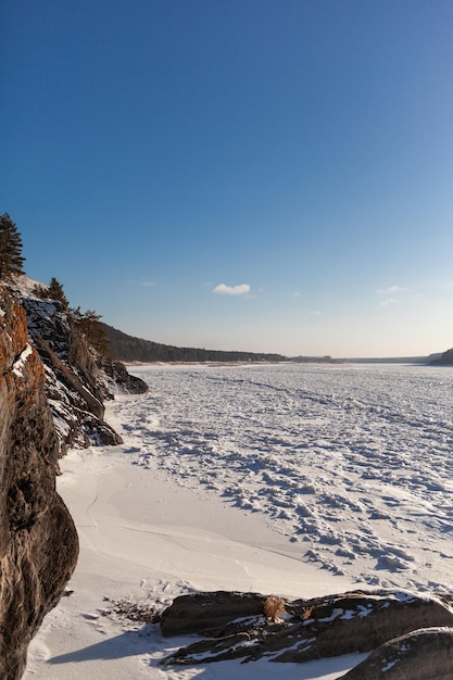 Un lago o río congelado en invierno. Cerca del bosque y las montañas en la nieve. paisajes de invierno