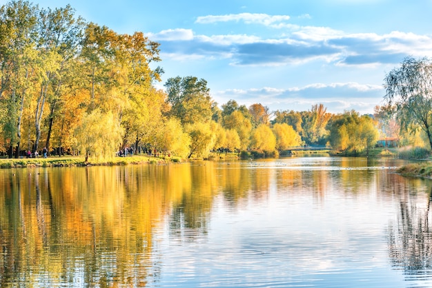 Lago con pájaros en el parque de la ciudad de otoño con poca gente