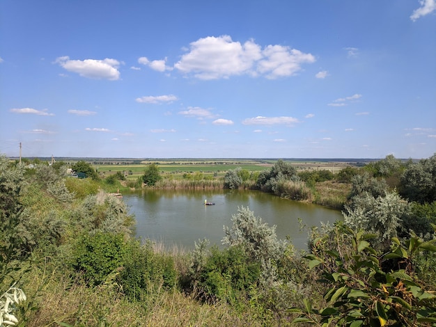 Un lago con un pequeño bote en primer plano y un cielo azul con nubes.