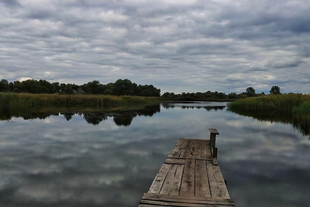 Un lago con un puente de madera, hermosas nubes en el cielo.