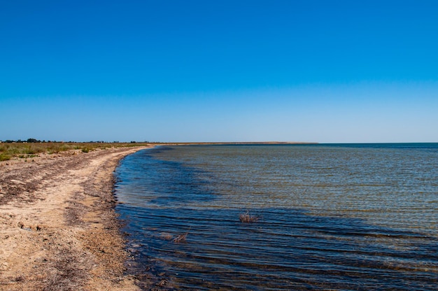 Lago salgado com praia de areia Paisagem com céu azul claro e ondas no lago