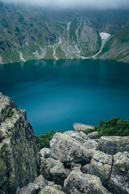 Lago de superficie azul profundo en el paisaje de niebla de montaña. Montañas Tatra, Czarny Staw, Polonia