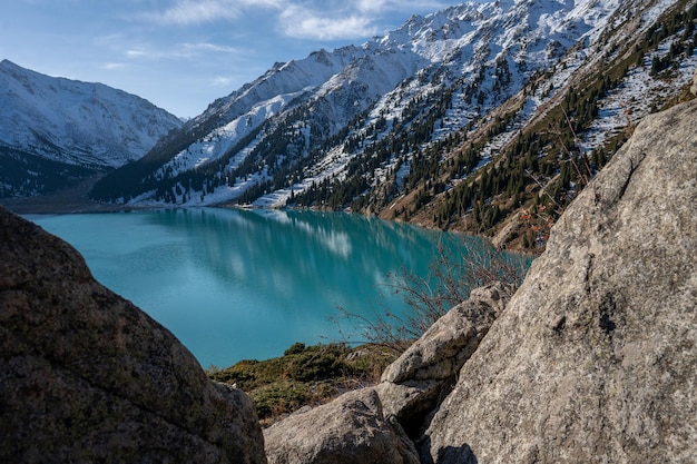 Lago turquesa rodeado de montañas nevadas en un día soleado