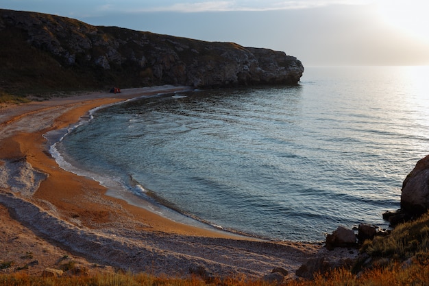 Lagoa do mar com uma praia de areia e uma tenda ao pôr do sol