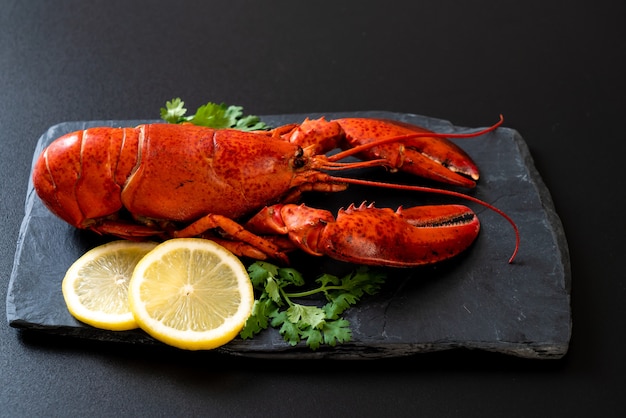 lagosta com legumes e limão no prato de ardósia preta