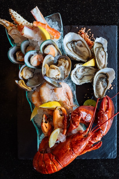 Lagosta cozida, ostras frescas, camarões, mexilhões e mariscos servidos em chapa de pedra preta.