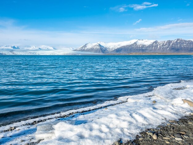 Laguna de iceberg de Jokulsarlon con glaciar y gran iceberg bajo un cielo azul nublado en Islandia