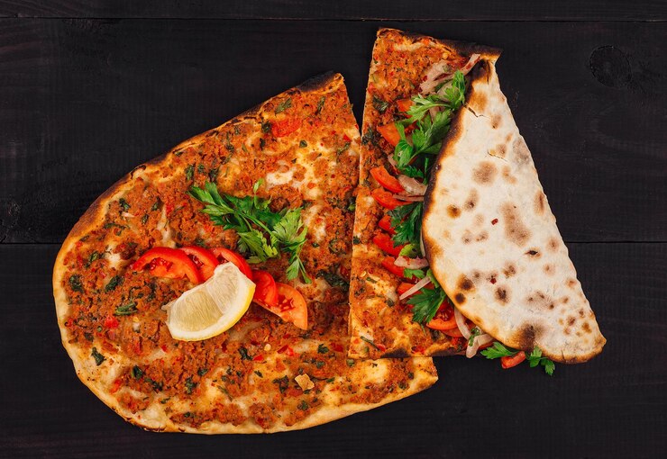 Lahmacun tradicional turco con carne picada y verduras sobre un fondo de madera oscura
