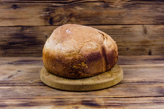 Laib frisch gebackenes Brot auf einem Holztisch