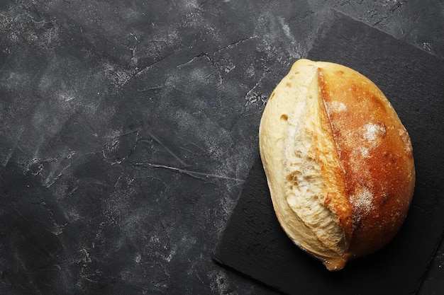 Laib hausgemachtes Brot auf einer dunklen Oberfläche mit Platz für Text. Frische Bäckerei.