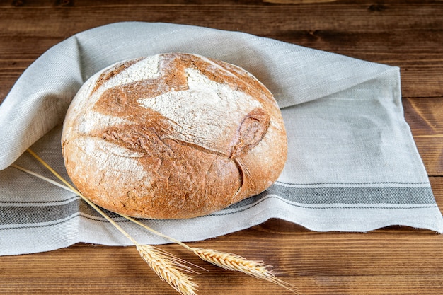 Laib integralen Brotes auf der Küchenserviette und auf dem Holztisch. Gesundes Getreidebrot.