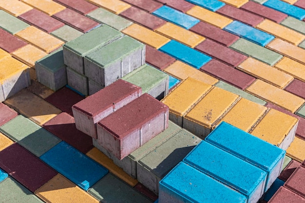 Lajes de pavimentação multicoloridas. Reparos de pavimentação e lajes de pavimentação na estrada, com cubos de azulejos ao fundo. Colocação de lajes de pavimentação na zona pedonal da cidade, beneficiação.