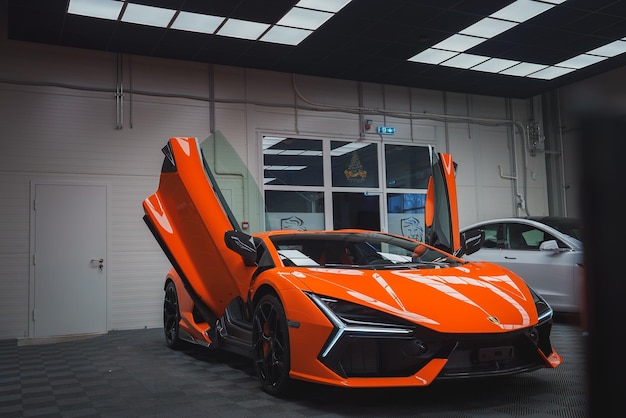 Lamborghini Revuelto naranja con puertas de tijera abiertas en la sala de exposiciones