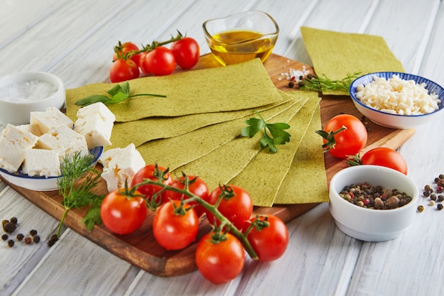 Láminas para hacer lasaña con espinacas e ingredientes tomates cherry, queso