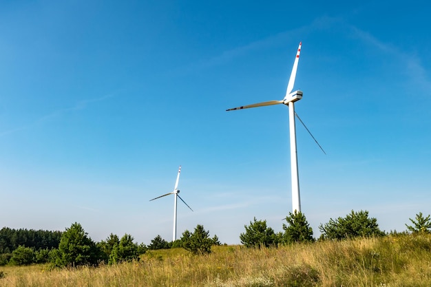 Lâminas rotativas de uma hélice de moinho de vento no fundo do céu azul Geração de energia eólica Energia verde pura