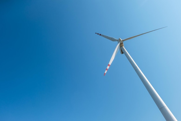 Lâminas rotativas de uma hélice de moinho de vento no fundo do céu azul  geração de energia eólica energia verde pura