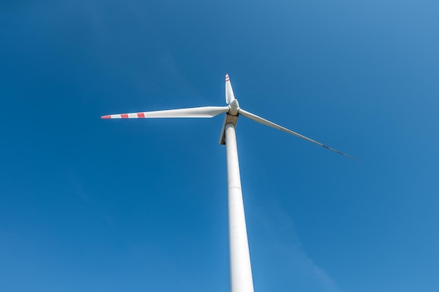 Lâminas rotativas de uma hélice de moinho de vento no fundo do céu azul Geração de energia eólica Energia verde pura