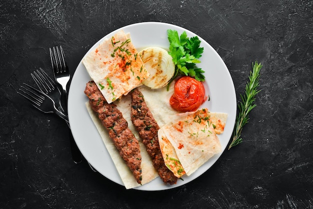 Lamm Kebab Fladenbrot und Gewürze auf schwarzem Hintergrund Ansicht von oben