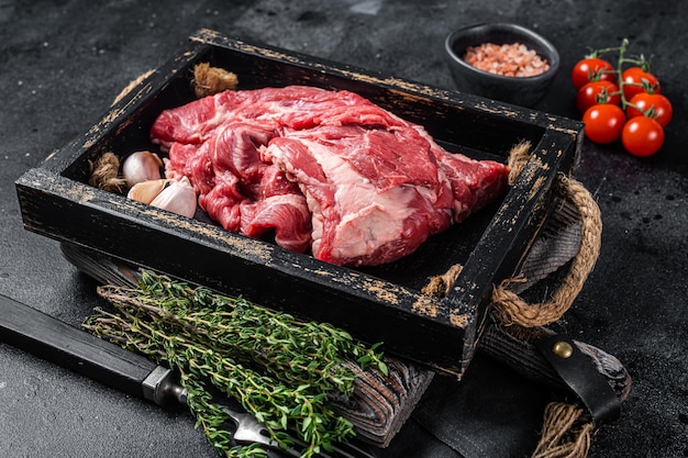 Lamm- oder Hammelhalsfleisch, rohes Fleisch ohne Knochen in Holzschale. Schwarzer Hintergrund. Ansicht von oben.