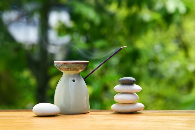 Lâmpada de aroma com incenso e pedras zen em uma mesa de madeira