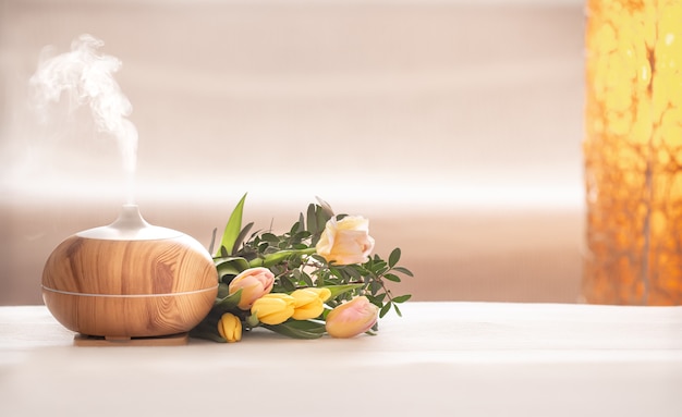 Lâmpada difusora de óleo de aroma em cima da mesa com um lindo buquê de tulipas primavera.