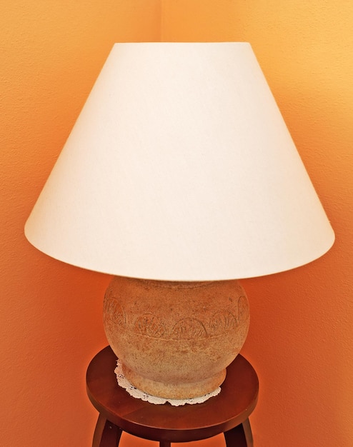Foto lâmpada em uma mesa de madeira com uma parede laranja ao fundo