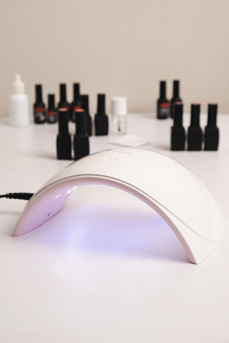 Foto lâmpada led ultravioleta para secagem de esmalte de unhas em gel e frascos com esmalte em gel