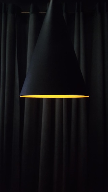 Lâmpada moderna no contexto das dobras das cortinas em cores escuras com espaço de cópia vertical