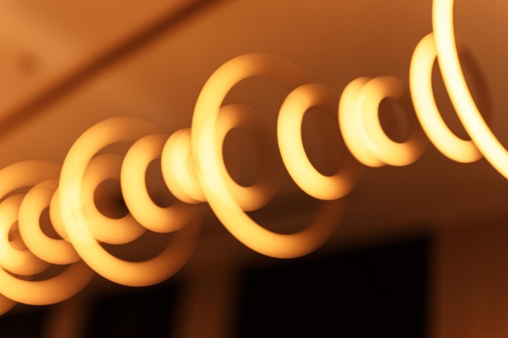 Foto lâmpada pendurada desfocada na forma de anéis desfoca a bela iluminação abstrata sob o teto da moderna eletricidade pingente lâmpadas redondas lustre brilhante amarelo dourado luz fraca dentro de uma sala