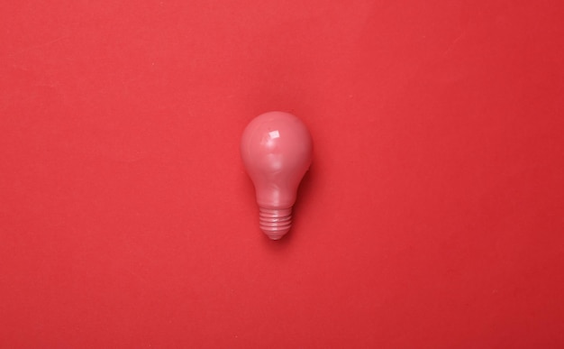 Lâmpada rosa sobre fundo vermelho Layout de minimalismo criativo Ideia fresca Arte conceitual Configuração plana Vista superior