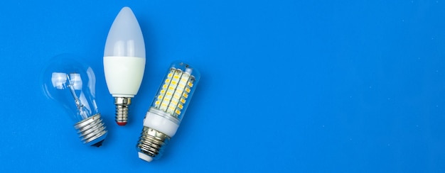 Lâmpadas diferentes juntas, fundo azul. Conceito de economia de energia. Faixa ampla, disposição plana, foto de vista superior